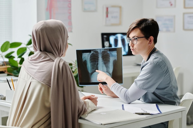 Radiologista feminina confiante mostrando o resultado do exame médico ao paciente