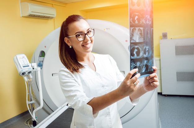 Foto radiologista feminina olhando o raio x na sala da tomografia computadorizada.