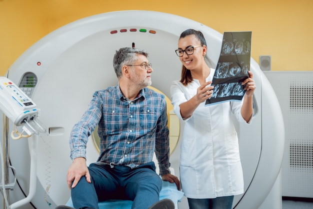 Radiólogo con un paciente masculino mirando rayos x.