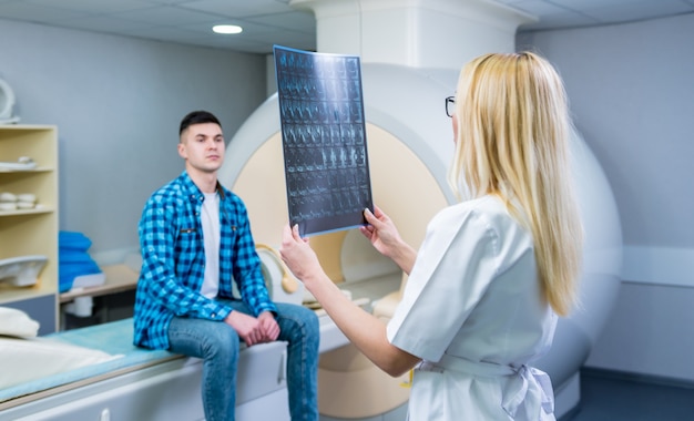 Foto radiólogo con un paciente masculino que examina una resonancia magnética.