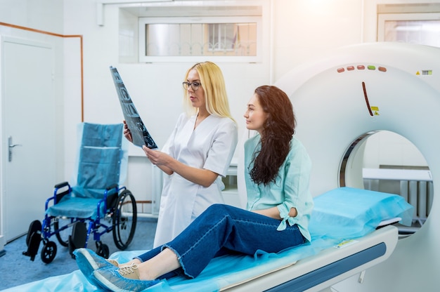 Radiólogo con una paciente que examina una tomografía computarizada.