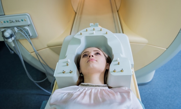 Radiólogo prepara a la joven para un examen cerebral por resonancia magnética