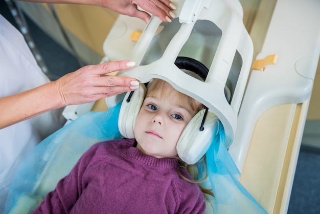 El radiólogo prepara a la niña para un examen cerebral por resonancia magnética