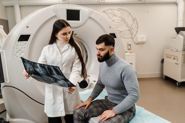 Foto radiólogo de tomografía computarizada que muestra una radiografía del abdomen a un paciente masculino en la sala de tomografía computarizada.