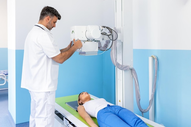 Foto radiólogos multiétnicos con una paciente joven en la sala de rayos x. radiólogo configurando la máquina para radiografiar a una paciente.