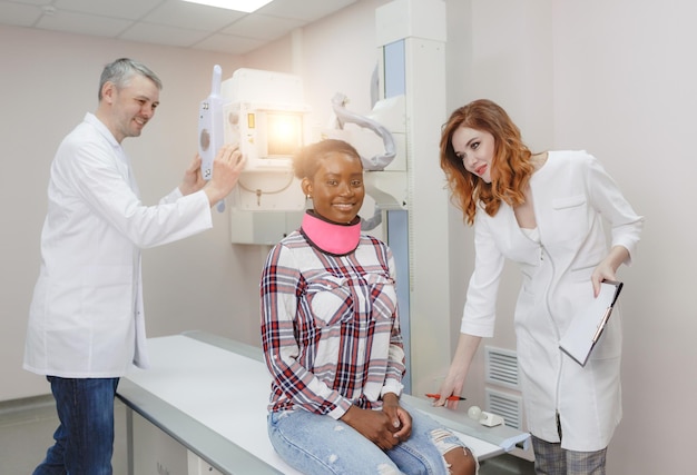 Los radiólogos preparan a un paciente afroamericano para obtener imágenes de rayos X en el laboratorio