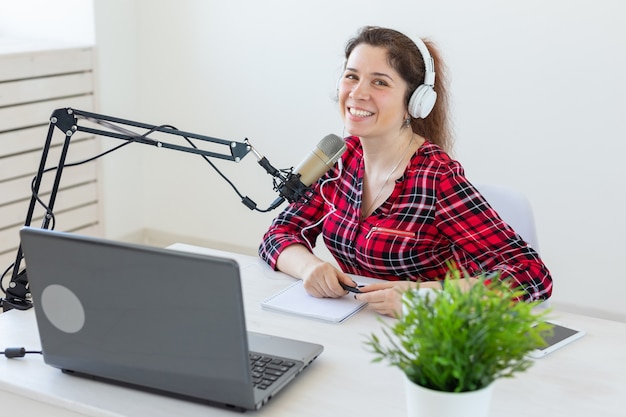 Radiomoderator-Konzept - Frau, die als Radiomoderatorin arbeitet, die vor Mikrofon auf weißem Hintergrund im Studio sitzt.