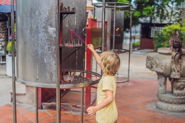 Räucherstäbchen auf Räucherstäbchen brennen und rauchen, um dem Buddha Respekt zu zollen, Räucherstäbchen in der Hand des Jungen und Rauch, um den Buddha im buddhistischen Leben zu respektieren