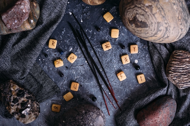 Räucherstäbchen zwischen den düsteren und esoterischen Utensilien Runensteinen