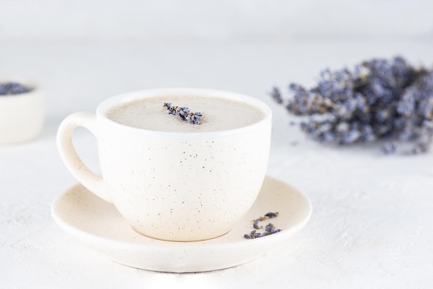 Raf-Kaffee mit Lavendelsirup in einer Tasse auf einem weißen Tisch. Zucker-, gluten- und laktosefrei und vegan.