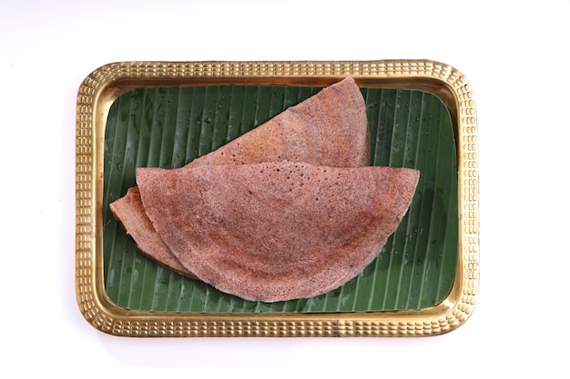 Ragi Dosa, desayuno saludable del sur de la India dispuesto en una placa de latón rectangular forrada con hoja de plátano.