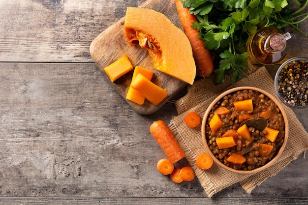 Ragout de estofado de lentejas con calabaza y zanahoria en un tazón sobre mesa de madera