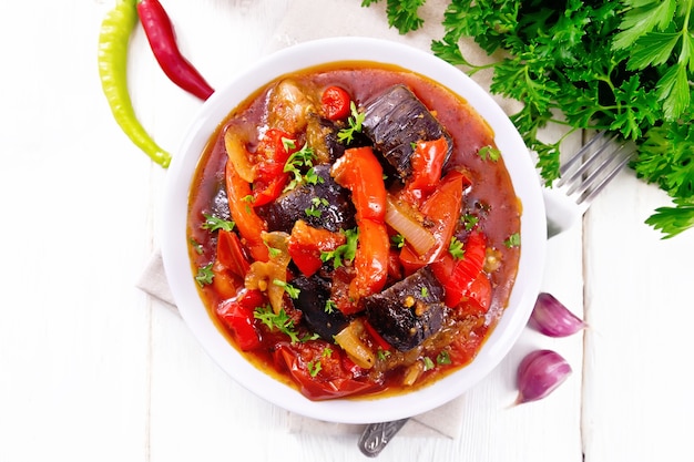 Ragu de vegetais com berinjela, tomate, pimentão, cebola e especiarias no prato na placa de madeira