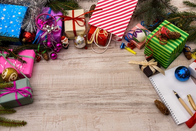 Rahmen aus Geschenkboxen und Tannenzweigen auf Holztisch. Weihnachtsfest