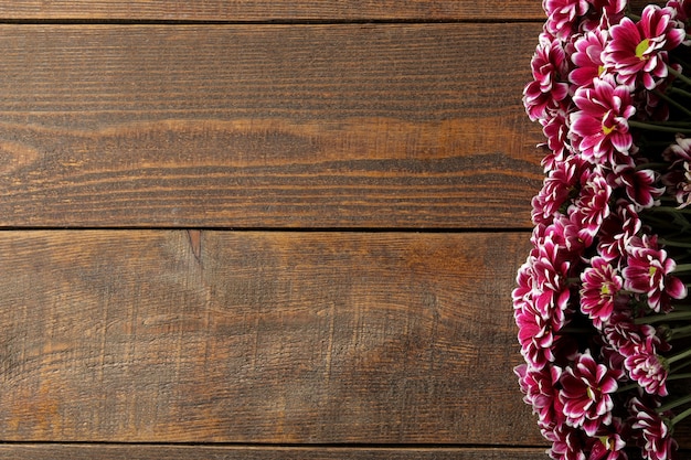 Rahmen aus Herbstblumen von Chrysanthemen auf einem braunen Holztisch mit Platz für eine Inschrift. Ansicht von oben