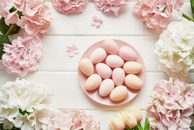 Rahmen aus rosa und beigen Hortensienblüten, rosa Eiern und gelben Tulpen