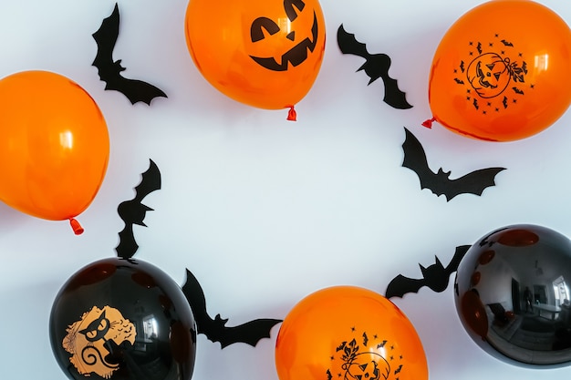 Rahmen aus schwarzen und orangefarbenen Halloween-Ballonen mit Kürbis- und Katzengesichtern und fliegenden Fledermäusen