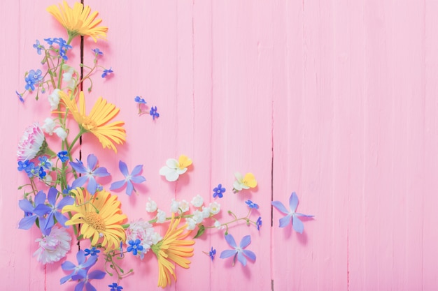 Rahmen der schönen Blumen auf rosa hölzernem Hintergrund