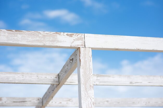 Rahmen einer Strandüberdachung aus Holzlatten, vor dem Hintergrund des blauen Himmels