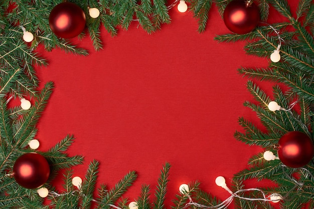 Rahmen eines Weihnachtskranzes auf rotem Grund. Foto mit Platz für Text.