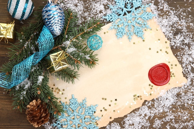 Rahmen mit Vintage-Papier und Weihnachtsschmuck auf Holzuntergrund