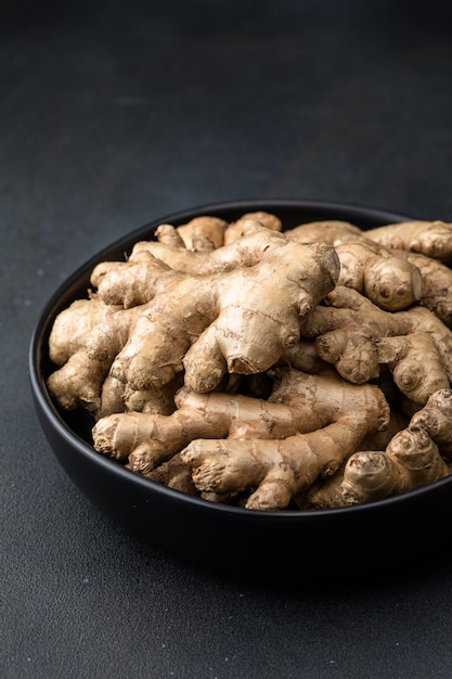 Raíces de jengibre del jardín en un plato en superficie negra