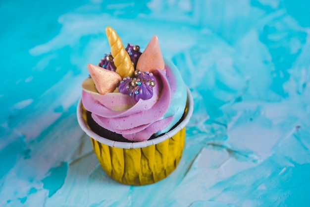 Rainbow unicorn cupcake en una taza amarilla. Una fiesta para una princesita.