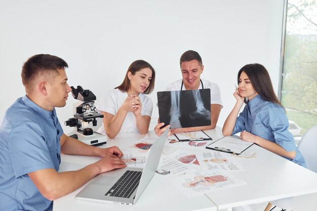 Raio X de pernas Grupo de jovens médicos está trabalhando juntos no escritório moderno