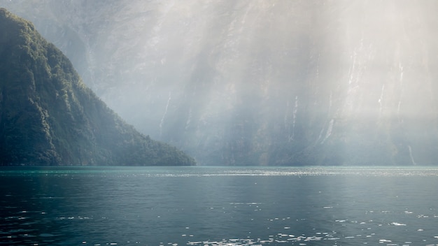 Raios de sol atingindo as profundezas do fiorde acentuando a cor esverdeada da água. Milford soundnova zelândia