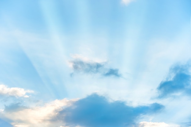 Raios de sol brilhando através da nuvem no céu azul do pôr do sol