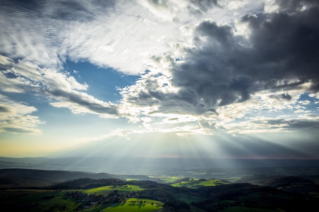 Raios de sol fluindo através de nuvens sobre a paisagem.
