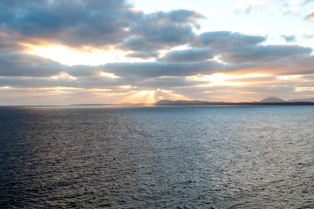 Raios de sol saindo das nuvens ao pôr do sol sobre o oceano