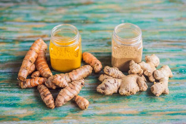 Raiz de gengibre e pó Raiz de cúrcuma e pó sobre um fundo de madeira colorido