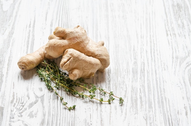 Raiz de gengibre fresco com tomilho em um fundo branco de madeira Fazenda de vegetais saudáveis e ecologicamente corretos Estilo rústico