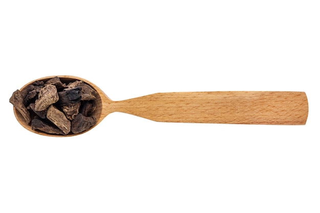 Raíz de inula seca en una cuchara de madera sobre un fondo blanco.