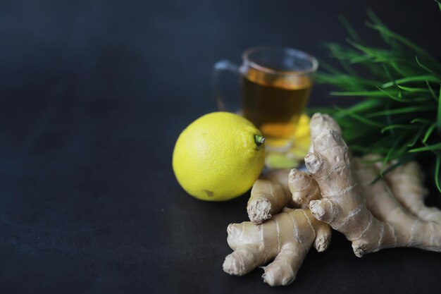 Raíz de jengibre entera y en rodajas. Té de jengibre con limón en el fondo oscuro. Raíz de jengibre fresco sobre fondo de piedra. vitaminas Vista superior. Espacio libre para su texto.