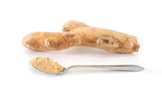 Raíz de jengibre fresco y jengibre en polvo en una cuchara aislada, especias saludables