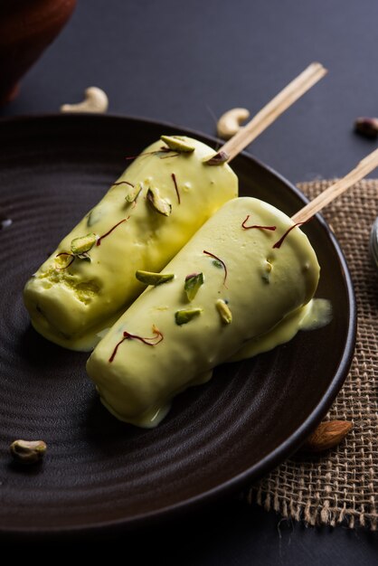 Rajasthani casero listo para comer matka kulfi - azafrán o kesariya con sabor a pistacho, anacardo y almendras, enfoque selectivo