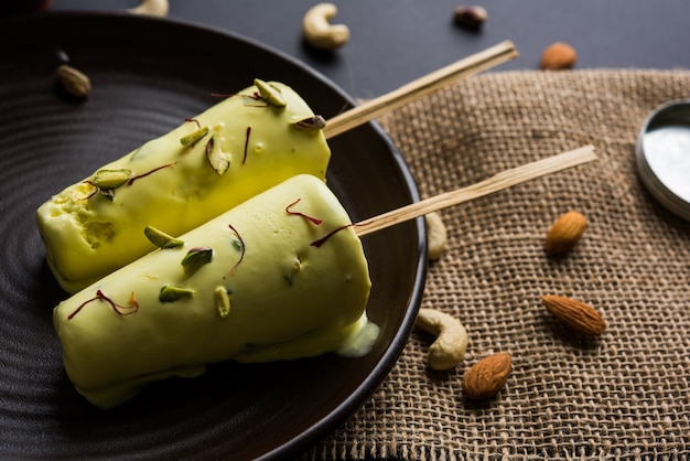 Rajasthani hausgemachte verzehrfertige Matka Kulfi - Safran oder Kesariya mit Pistazien-, Cashew- und Mandelgeschmack, selektiver Fokus