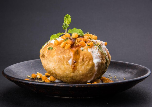 Rajasthani Shahi Raj Kachori, gefüllt mit Kartoffel-Sprossen-Füllung. serviert mit Quark, Chutney und Sev in einem Teller, isoliert auf buntem oder hölzernem Hintergrund. selektiver Fokus