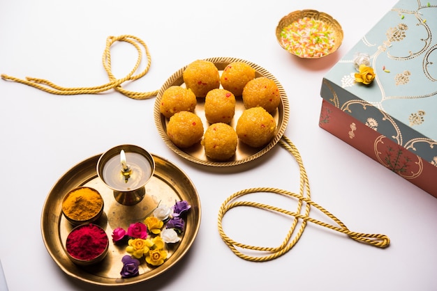 Raksha-Bandhan-Festival: konzeptionelles Rakhi, das mit einem Teller voller Bundi Laddu-Süßigkeiten mit Band und Pooja Thali hergestellt wird. Ein traditionelles indisches Armband - Symbol der Liebe zwischen Bruder und Schwester