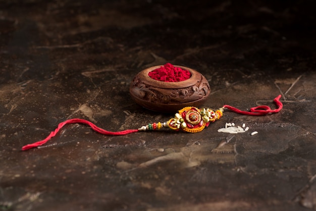 Raksha Bandhan Hintergrund mit einem eleganten Rakhi, Reiskörnern und Kumkum