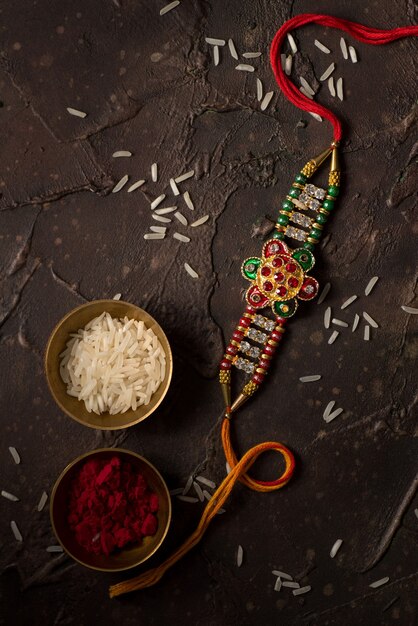 Raksha Bandhan Hintergrund mit einem eleganten Rakhi, Reiskörnern und Kumkum