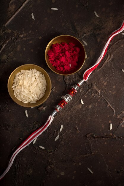 Raksha Bandhan Hintergrund mit einem eleganten Rakhi, Reiskörnern und Kumkum