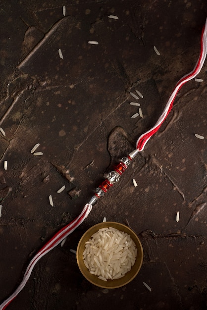 Raksha Bandhan Hintergrund mit einem eleganten Rakhi, Reiskörnern und Kumkum