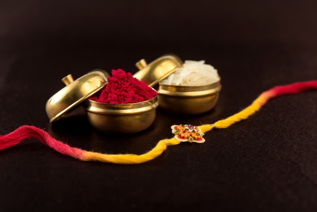 Raksha Bandhan Hintergrund mit einem eleganten Rakhi, Reiskörnern und Kumkum