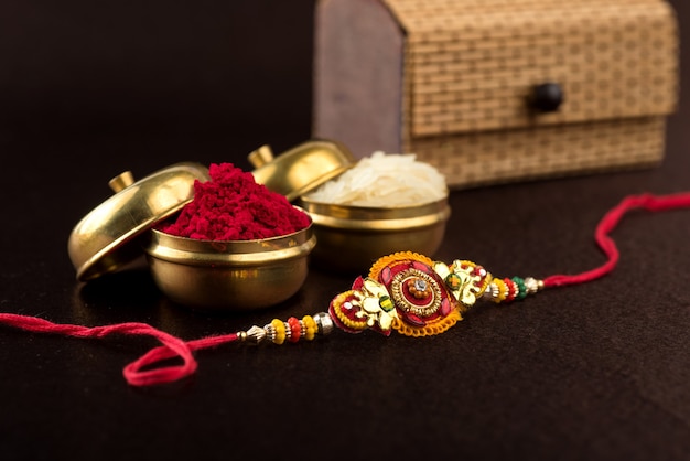 Raksha Bandhan Hintergrund mit einem eleganten Rakhi, Reiskörnern und Kumkum