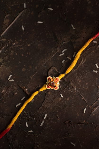 Raksha Bandhan Hintergrund mit einem eleganten Rakhi und Streureis