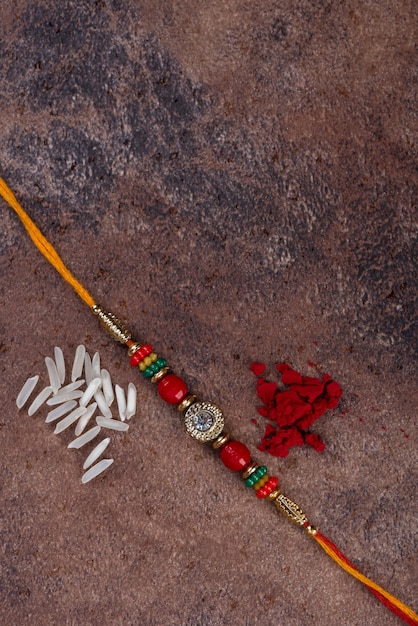 Raksha bandhan: rakhi com grãos de arroz e kumkum em fundo de pedra