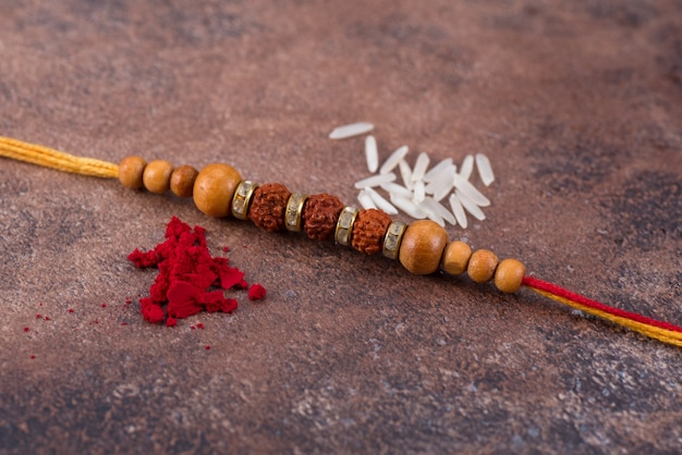 Raksha Bandhan: Rakhi con granos de arroz y kumkum sobre fondo de piedra